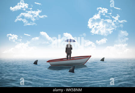 Businessman holding umbrella contre les requins encerclant petit bateau dans l'océan Banque D'Images