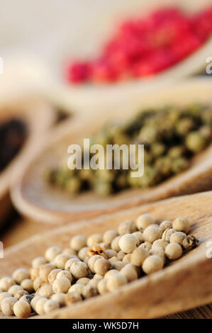 Assorted peppercorns dans la cuisine en bois macro cuillères Banque D'Images