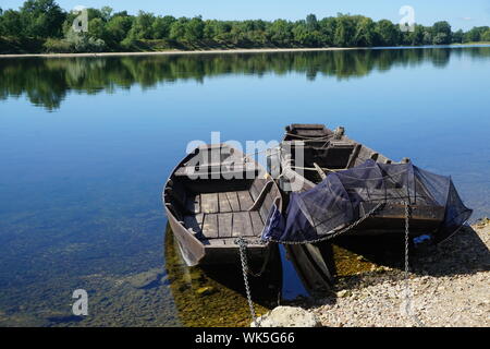 Reflet miroir de la forêt et de vieux bois bateaux plats avec filet de pêche sur la Loire en France Banque D'Images