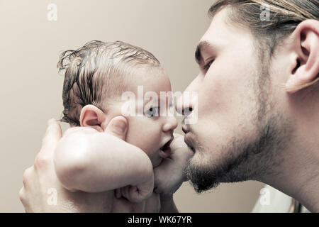 Père avec son jeune bébé de câliner et l'embrasser sur la joue. La paternité, l'amour. Banque D'Images