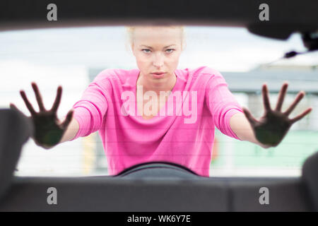 Auto-suffisant, strong, jeune femme poussant une voiture. Panne moteur. Banque D'Images