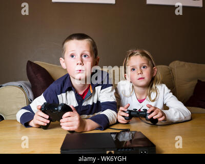 Siblings playing Video Games sitting in the sofa Banque D'Images