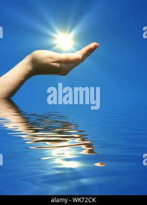 Main tenant le soleil et l'eau reflaction avec copyspace Banque D'Images