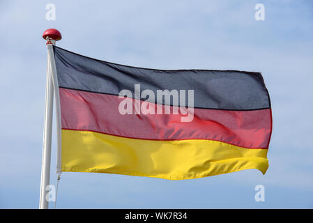 Brandir le drapeau allemand sur le vent contre le ciel bleu Banque D'Images