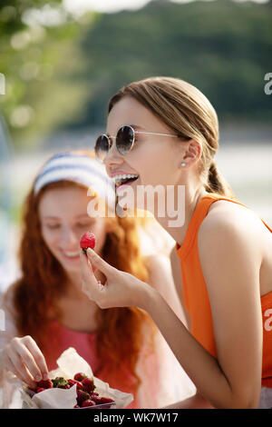 Belle femme sunglasses smiling while eating strawberry Banque D'Images