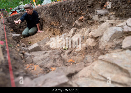 03 septembre 2019, la Saxe-Anhalt, Harzgerode : Le directeur d'excavation Anna Bartrow, archéologue à l'université de Halle, s'accroupit dans une section du site d'excavation de la 'Wüstung Mapochana' et examine la paroi du puits dans lequel elle soupçonne les vestiges d'un ancien four. Le règlement couvre environ 11 hectares et a été fondée entre le 11ème et 12ème siècles. Le village a été abandonné dès le 15e siècle. Le village est l'un d'environ 100 dans la région du Harz, qui a disparu au Moyen Âge et sont maintenant appelés zones désertées. Les fouilles sont importants parce qu'il y a fort Banque D'Images