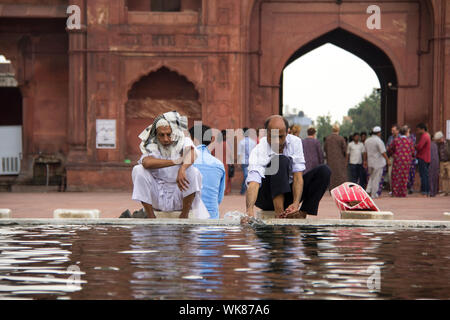 Indian Muslim men perform ritual wudhu before namaz at a mosque, Jama Masjid, Old Delhi, India Stock Photo