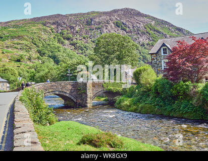 Vue d'un pont en pierre sur la rivière Glaslyn circulant dans la ville de sur un jour étés de Beddgelert, Snowdonia, Gwynedd, Pays de Galles, Royaume-Uni Banque D'Images