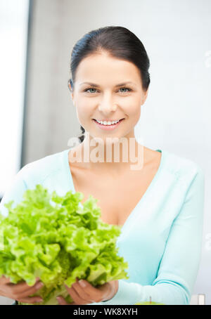 Belle femme dans la cuisine avec des feuilles de salade verte.. Banque D'Images