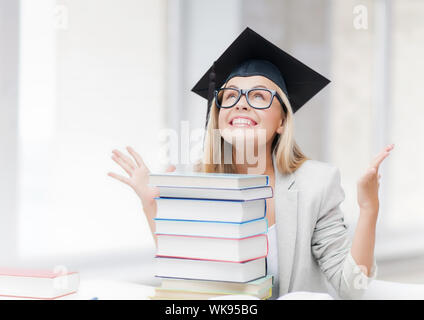 Happy student in graduation cap avec pile de livres Banque D'Images