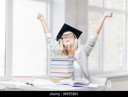 Happy student in graduation cap avec pile de livres Banque D'Images