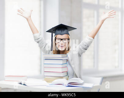 Happy student in graduation cap avec pile de livres Banque D'Images