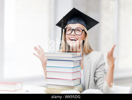 Happy student in graduation cap avec pile de livres Banque D'Images