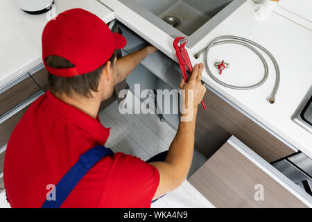 Services de plomberie - plombier travaillant dans la cuisine domestique, la réparation des tuyaux de l'évier Banque D'Images