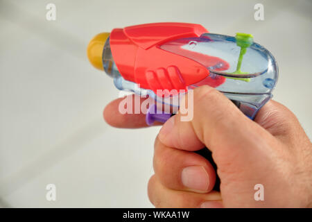 Un pistolet à eau dans un homme de race blanche main devant un fond blanc sur une journée ensoleillée Banque D'Images