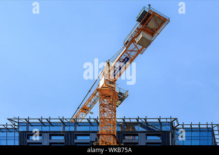 Un fragment de la toiture de la façade d'une maison en construction, un bâtiment moderne est en cours de construction, une grue a tour est situé au-dessus du toit contre Banque D'Images