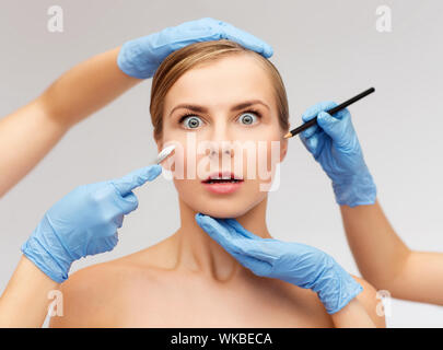 Santé, médecine et beauté concept - belle femme visage et mains esthéticienne avec crayon et scalpel Banque D'Images