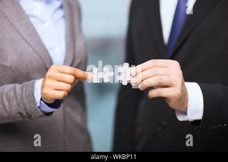 Concept d'affaires et de bureau - businessman and businesswoman essayez de connecter des pièces de puzzle in office Banque D'Images