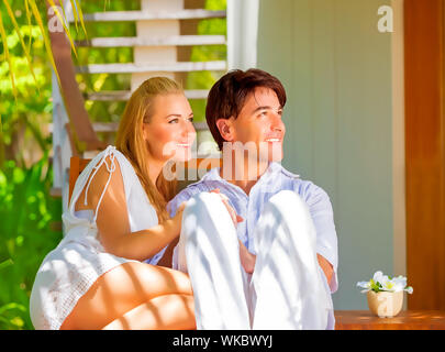 Cute couple heureux s'amuser en plein air, assis sur des transats sur le luxe tropical resort, journée ensoleillée, romantique des vacances d'été, l'amour concept Banque D'Images