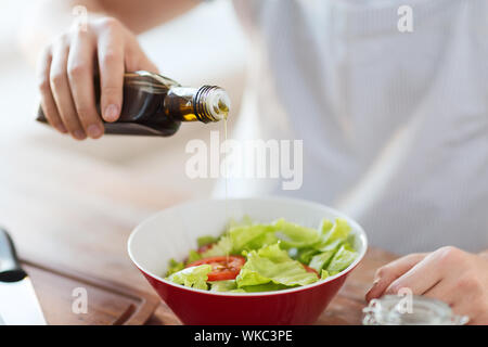 La cuisine et accueil concept - close up of male hands l'assaisonnement salade dans un bol avec l'huile d'olive Banque D'Images