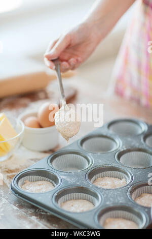 La cuisine et accueil concept - remplissage de moules à muffins avec la pâte Banque D'Images