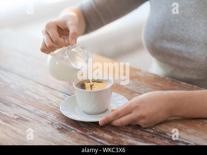 La nourriture et accueil concept - close up of female verser le lait dans le café Banque D'Images