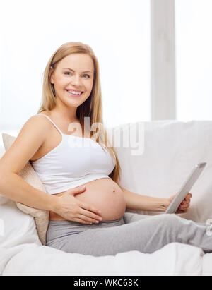 Smiling pregnant woman with tablet PC ordinateur Banque D'Images