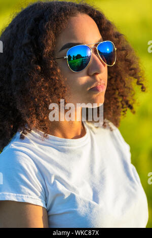 Belle et happy mixed race African American biracial femme fille enfant adolescent jeune femme en portant des lunettes de soleil coucher de soleil Banque D'Images