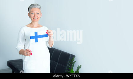 Portrait femme scandinave mature est titulaire d'un drapeau de la Finlande. Banque D'Images