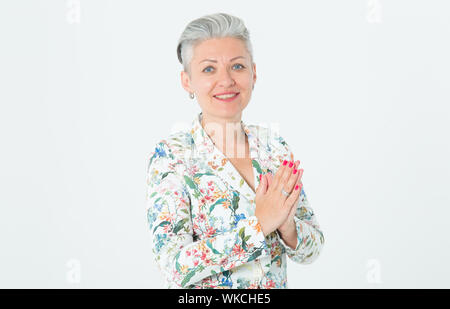 Portrait d'une belle femme d'âge moyen. Heureux femelle avec les cheveux gris dans une veste ressemble à l'appareil debout sur un fond clair. Banque D'Images