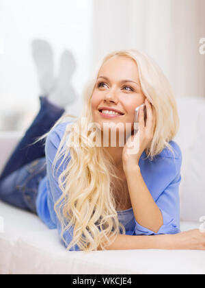 Smiling woman with smartphone à la maison Banque D'Images