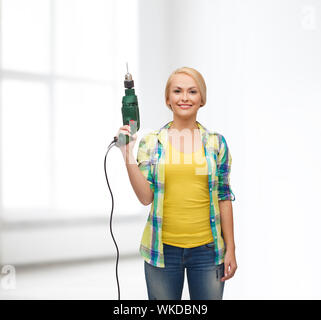 La réparation, la construction et l'entretien concept - smiling woman with drill machine Banque D'Images