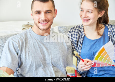 Jeune couple comme une amélioration de l'habitat avec le pinceau et couleurs en choisissant la bonne couleur du mur Banque D'Images