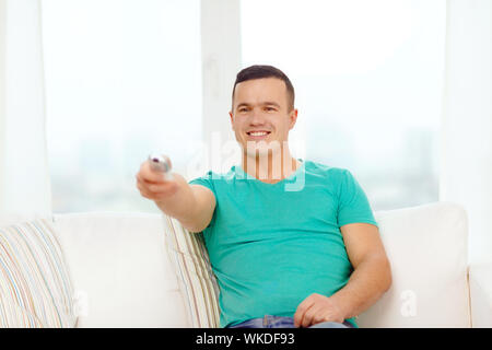 Accueil, de la technologie et de l'entretainment concept - smiling man with tv remote control à la maison Banque D'Images