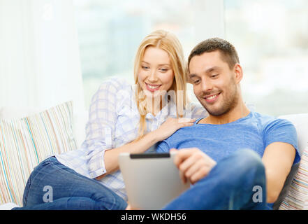 L'amour, la famille, la technologie, internet et le bonheur concept - smiling couple heureux witl tablet pc ordinateur à domicile Banque D'Images