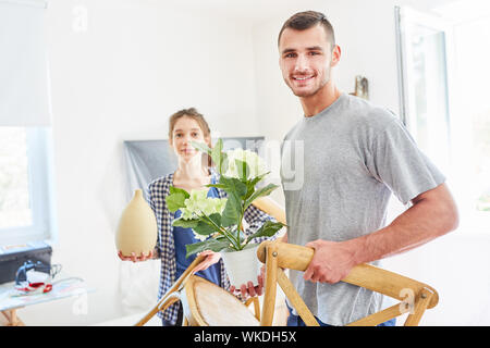 Jeune couple porte meubles et plantes quand déplacer ou déménager dans le nouvel appartement Banque D'Images