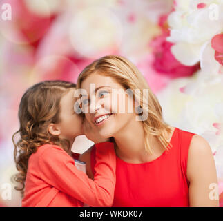 Smiling mother and daughter whispering gossip Banque D'Images