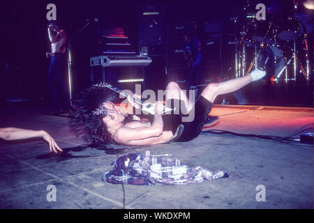 Angus Young de AC/DC joue de la guitare sur le dos, sur scène au Palladium Theater à New York en juin 1979. Bon Scott est chanté dans l'arrière-plan, et il y a un bras et la main visible dans la photo. Banque D'Images