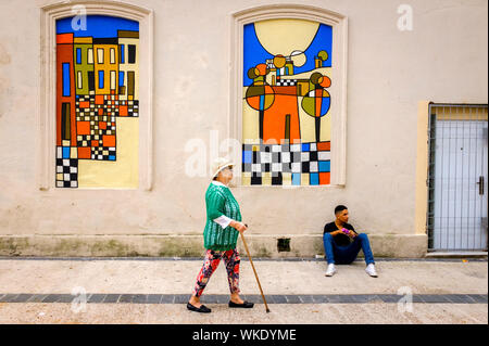 Uruguay : Montevideo ; Calle Emilio Reus, une rue aux façades colorées et de belles maisons avec des murs peints par des artistes locaux. Jeune homme assis aga Banque D'Images