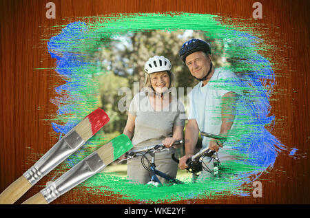 Image composite de couple sur les vélos dans le parc contre table en chêne en bois avec les pinceaux Banque D'Images