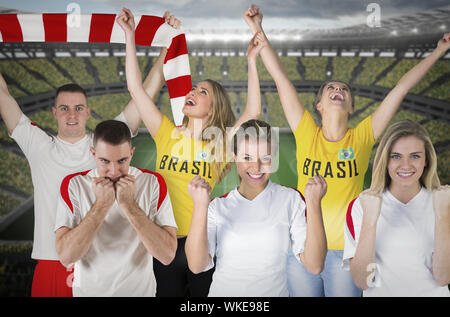 Image composite de plusieurs fans de football contre le grand stade de football avec les fans en jaune Banque D'Images