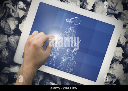 Image composite de hand touching tablet showing team holding up light bulb Banque D'Images