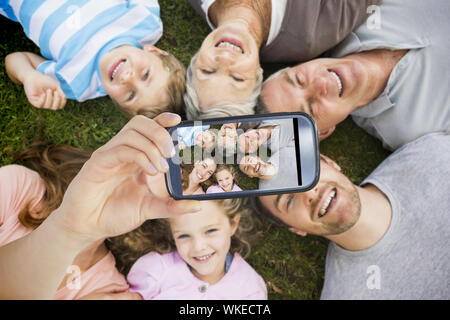 Hand holding smartphone montrant couché dans la famille élargie au cercle park Banque D'Images