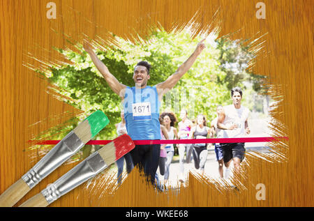 Image composite de racer crossing ligne d'arrivée avec le pinceau imbibé de rouge contre table en pin en bois Banque D'Images