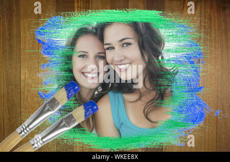 Image composite d'amis smiling at camera avec le pinceau trempé dans blue contre surface en bois avec des planches Banque D'Images