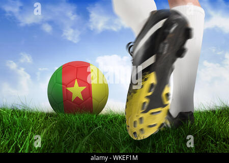 Composite image kicking football cameroun ball contre un champ d'herbe sous ciel bleu Banque D'Images