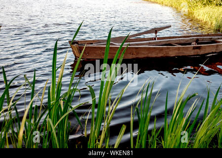 Une petite barque en bois avec un fond sur un lac calme près de la rive. Bélarus Banque D'Images