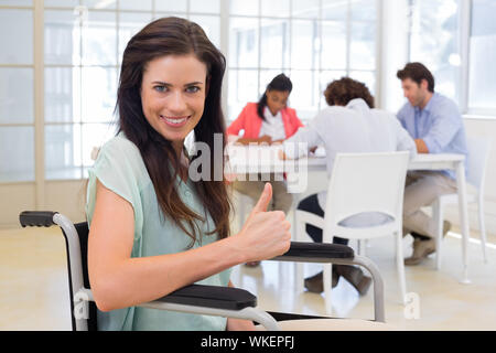 Businesswoman with Thumbs up donne d'invalidité à l'appareil photo au bureau Banque D'Images