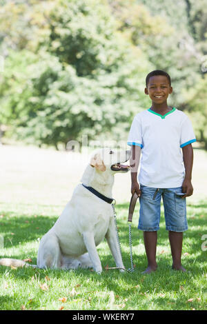 Petit garçon debout avec son animal labrador dans le parc par une journée ensoleillée Banque D'Images