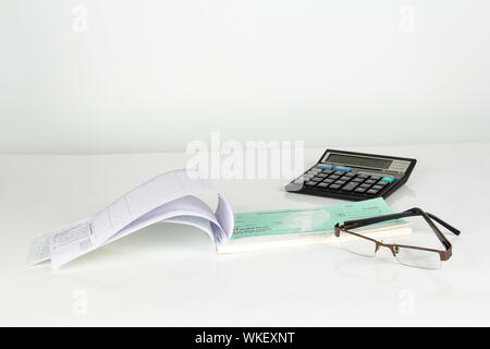 Empty cheque book with calculator and eyeglasses Stock Photo
